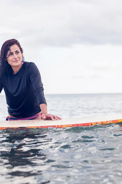 Schöne junge Frau mit Surfbrett im Wasser — Stockfoto