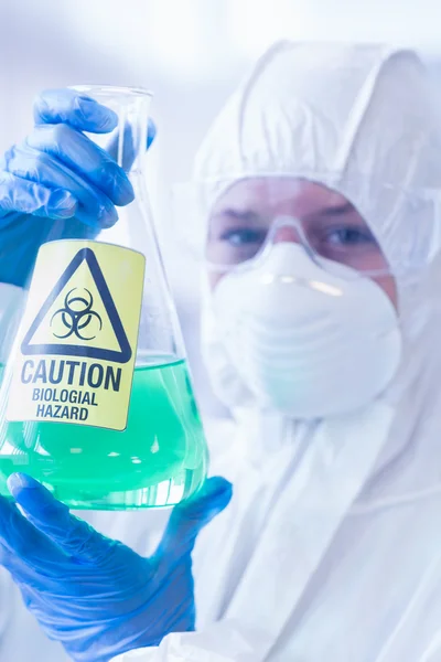 Scientifique en combinaison de protection avec produit chimique dangereux en fiole — Photo