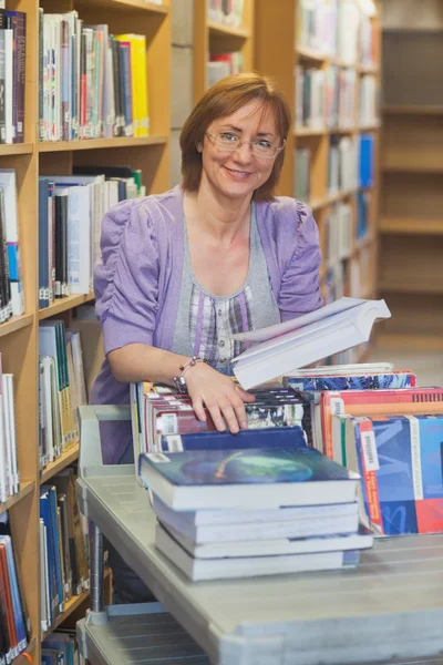 Zufriedene Bibliothekarin, die Bücher zurückgibt — Stockfoto