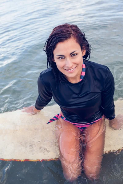 Retrato de uma bela mulher sentada na prancha de surf na água — Fotografia de Stock