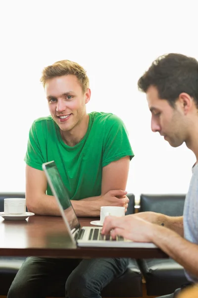 Studenten met behulp van laptop terwijl het hebben van koffie bij coffee shop — Stockfoto