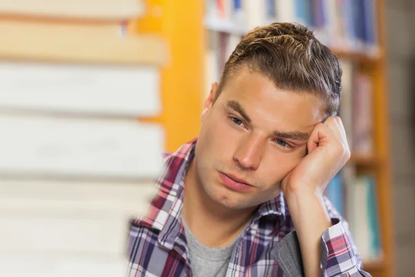 Stanco bello studente che studia tra mucchi di libri — Foto Stock