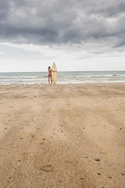 Mujer tranquila en bikini con tabla de surf en la playa —  Fotos de Stock