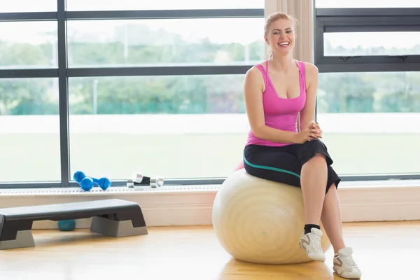 Glad kvinna sitter på övning boll i fitnesstudio — Stockfoto