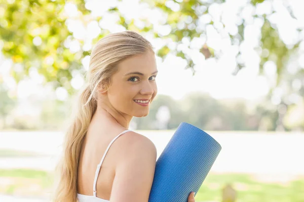 Hermosa mujer deportiva posando sosteniendo una alfombra de ejercicio — Foto de Stock