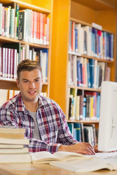 Handsome smiling student using computer — Stock Photo, Image