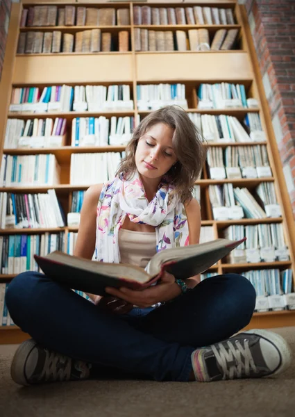 Estudiante contra estantería leyendo un libro en la biblioteca f —  Fotos de Stock