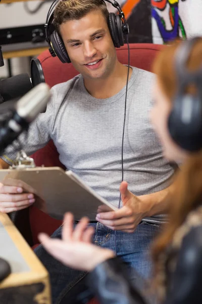 Atraente apresentador de rádio entrevistando um hóspede segurando prancheta — Fotografia de Stock
