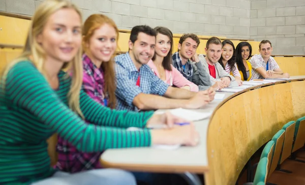 Usmívající se studenti sedící v řadě v přednáškovém sále — Stock fotografie