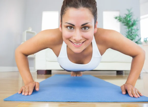 Ajuste mujer joven practicando press ups en una alfombra de ejercicio azul —  Fotos de Stock