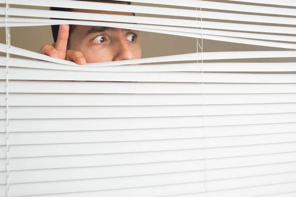 Scared male eyes spying through roller blind — Stock Photo, Image