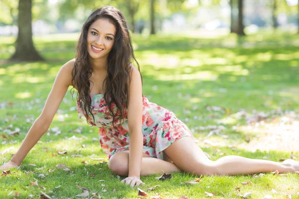 Stijlvolle lachende brunette zittend op het gras — Stockfoto
