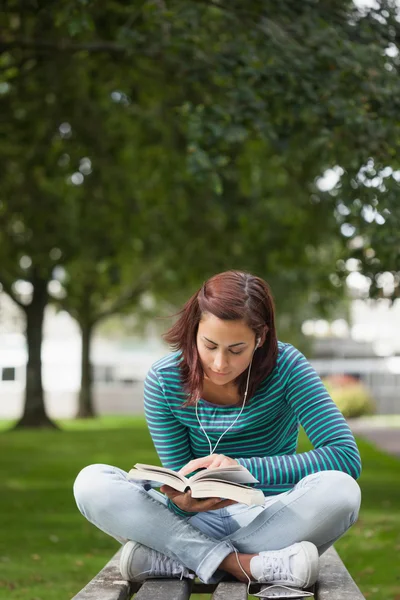 Focused casual student sitting on bench reading — Stock Photo, Image