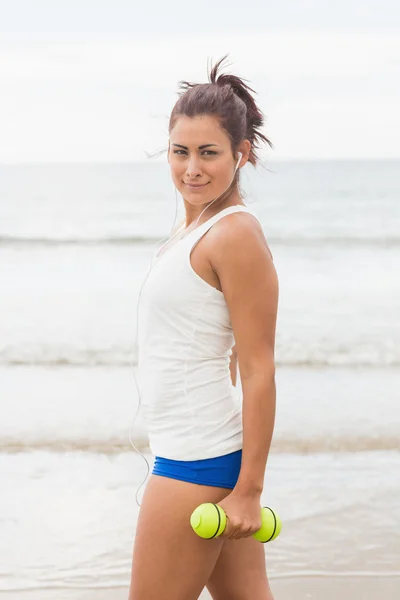 Preciosa joven sosteniendo pesas posando en la playa —  Fotos de Stock