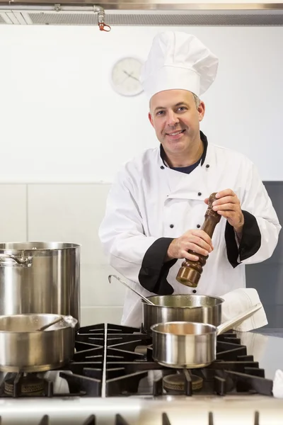 Lachende chef-kok met behulp van pepermolen. — Stockfoto