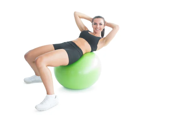 Mujer en forma alegre haciendo un ejercicio en una pelota de ejercicio — Foto de Stock