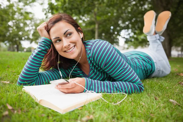 Lächelnder lässiger Student, der im Gras liegt und Musik hört — Stockfoto