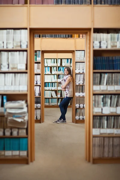 Повна довжина студентки, що стоїть у бібліотеці — стокове фото
