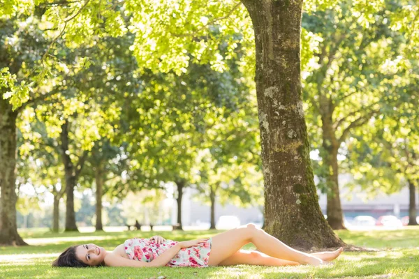 Stylish attractive brunette lying on a lawn — Stock Photo, Image