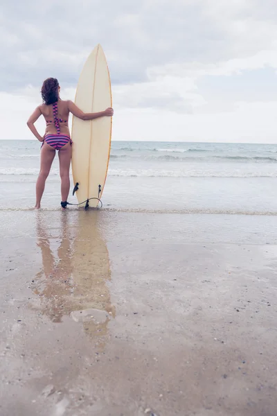 Slanke vrouw in bikini met surfboard op strand — Stockfoto