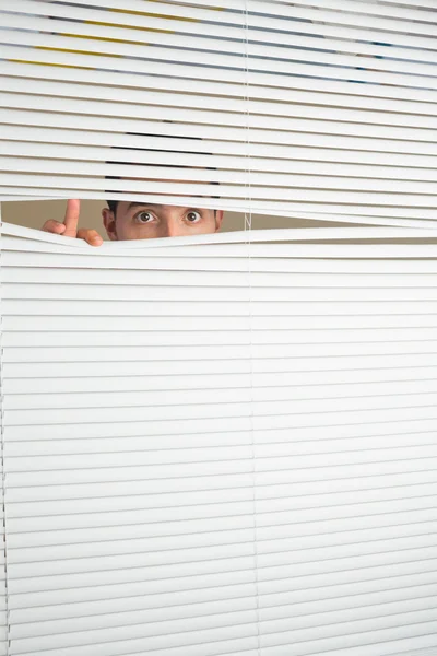 Espantado masculino olhos espionagem através de rolo cego — Fotografia de Stock