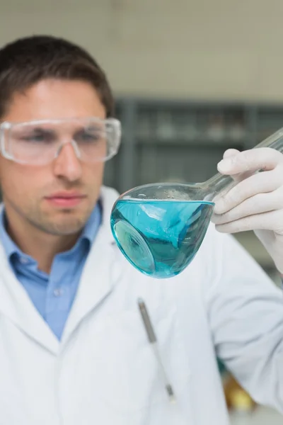 Mannelijke onderzoeker kijken kolf met blauwe vloeistof in het lab — Stockfoto