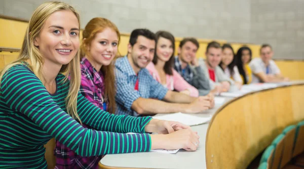 Estudiantes sonrientes sentados en fila en la sala de conferencias — Foto de Stock