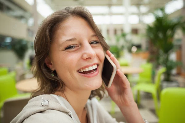 Vrolijke vrouw met behulp van mobiele telefoon in de cafetaria — Stockfoto