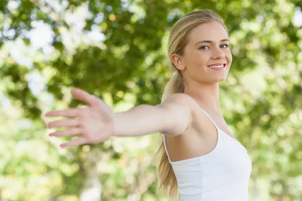 Giovane donna in forma che fa yoga in un parco allargando le braccia — Foto Stock