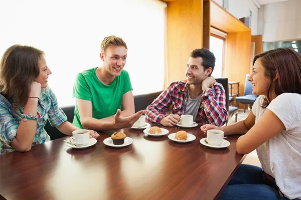 Cuatro estudiantes casuales tomando una taza de café charlando — Foto de Stock