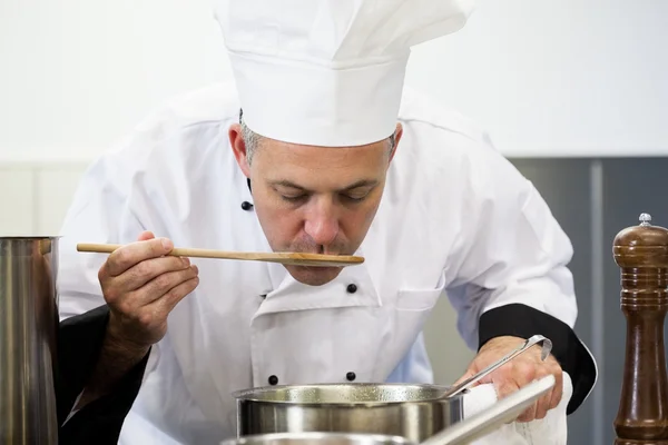 Focused head chef tasting sauce with wooden spoon — Stock Photo, Image