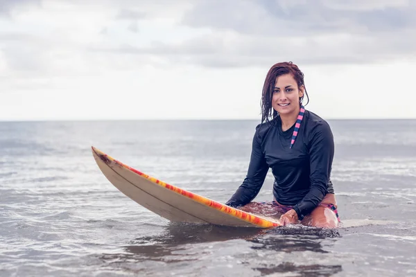 Piękna kobieta siedzi na deskę surfingową w wodzie — Zdjęcie stockowe