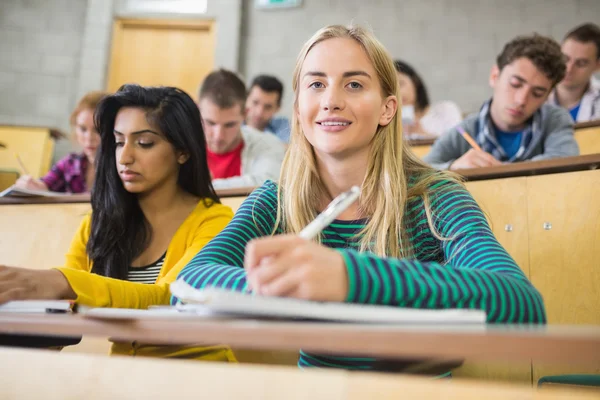 Estudiantes escribiendo notas en la sala de conferencias — Foto de Stock