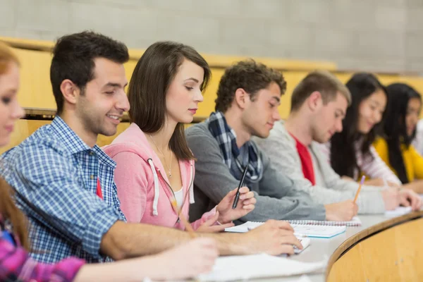 Estudiantes escribiendo notas seguidas en la sala de conferencias —  Fotos de Stock