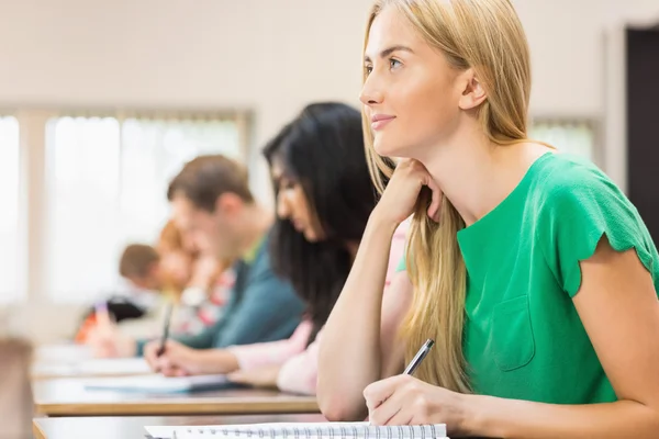 Jovens estudantes escrevendo notas em sala de aula Imagem De Stock