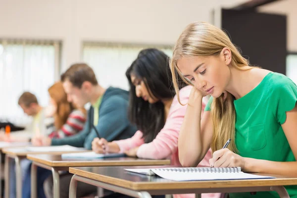 Young students writing notes in classroom Stock Image