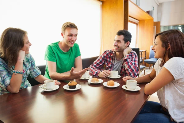 Four casual students having a cup of coffee chatting Stock Picture
