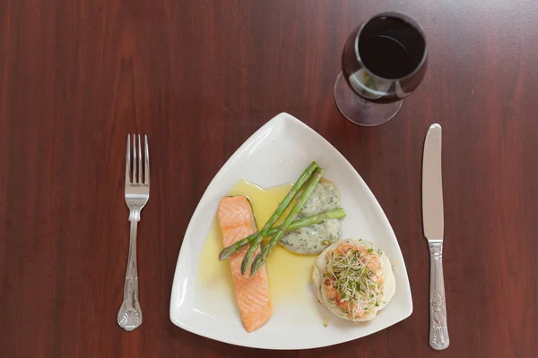 Overhead view of salmon dish with asparagus and red wine — Stock Photo, Image