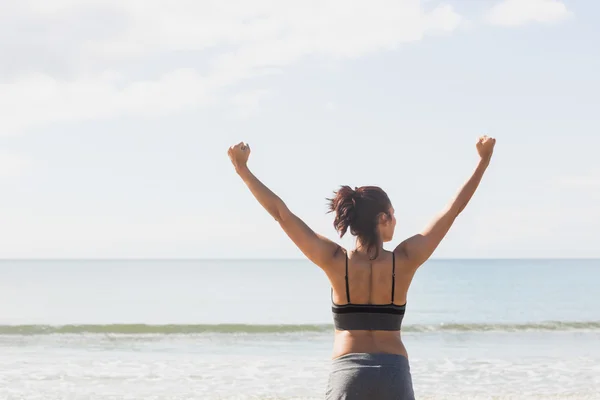 Härlig smal kvinna stretching hennes armar på stranden — Stockfoto