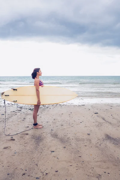 Vista lateral de una mujer llevando tabla de surf en la playa —  Fotos de Stock