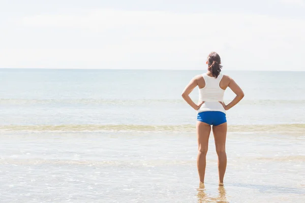 Donna in forma snella in piedi sulla spiaggia — Foto Stock