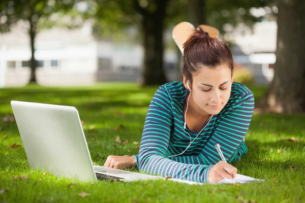 Gelegenheitsstudent, der im Gras liegt und Notizen macht — Stockfoto
