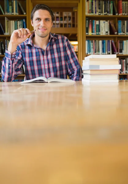 ライブラリ内の机で勉強して成熟した学生の笑みを浮かべてください。 — ストック写真