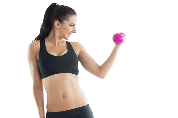 Mujer delgada alegre entrenando su brazo usando una mancuerna rosa —  Fotos de Stock