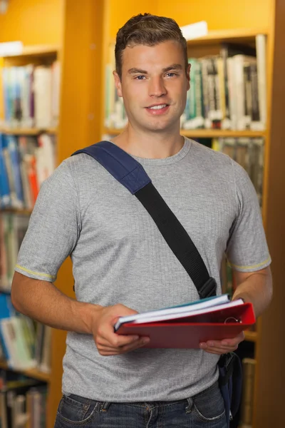 Bonito sorrindo estudante segurando pasta e cadernos — Fotografia de Stock