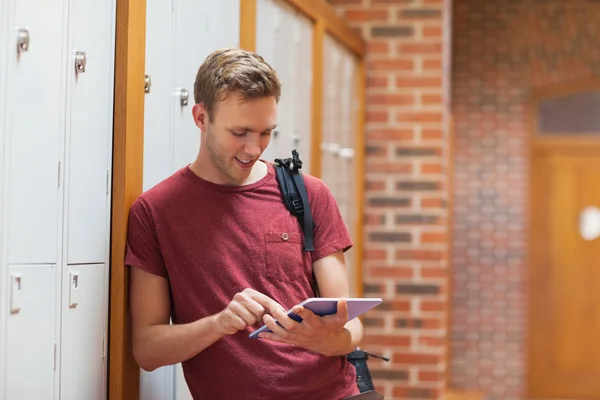 Estudante bonito inclinado contra armários usando tablet — Fotografia de Stock