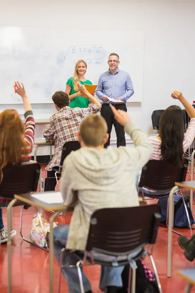 Students raising hands in the classroom — Stock Photo, Image