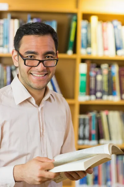 Sorrindo estudante maduro com livro na biblioteca — Fotografia de Stock