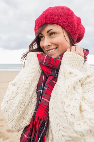 Nette lächelnde Frau in warmer Kleidung, die am Strand wegschaut — Stockfoto