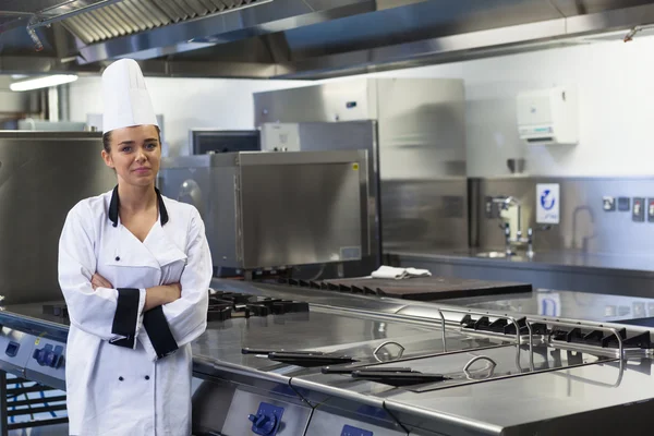 Giovane chef felice in piedi accanto a braccia di superficie di lavoro incrociate — Foto Stock